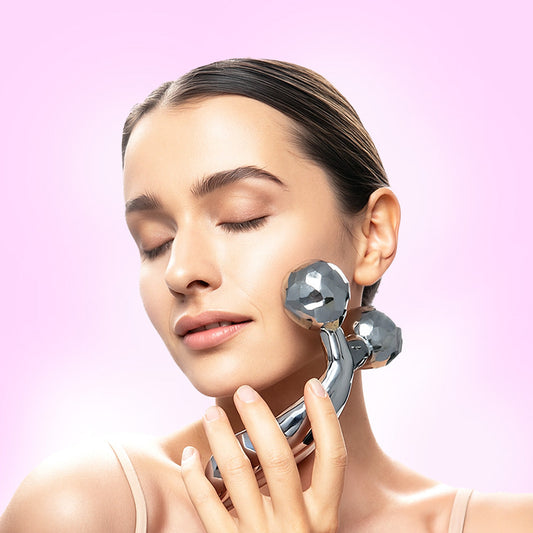 Woman using a skincare device on her face against a pink background